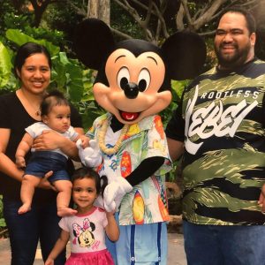 family standing with Mickey Mouse charging their battery