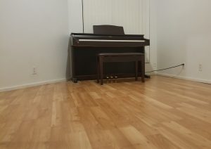 electric upright piano standing still alone in a room